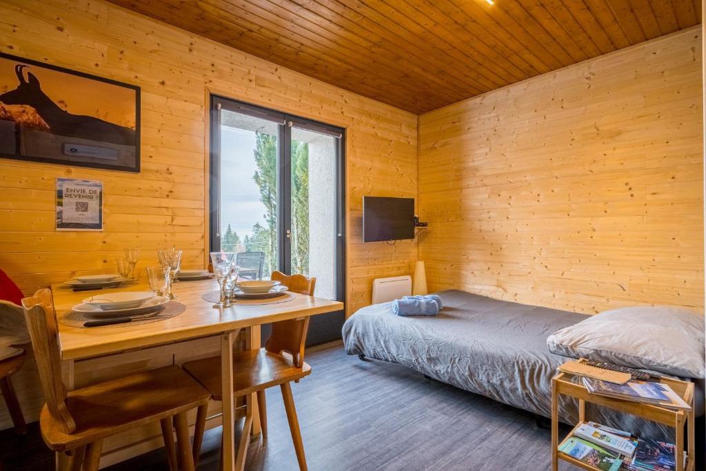 una camera da letto con un letto, un tavolo e una finestra di Charmant studio au cœur d’une station des Vosges a Sondernach