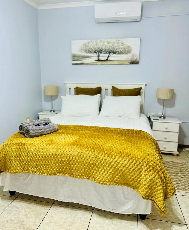 a bedroom with a large bed with a yellow blanket at O'Meara Overnight Rooms in Kimberley