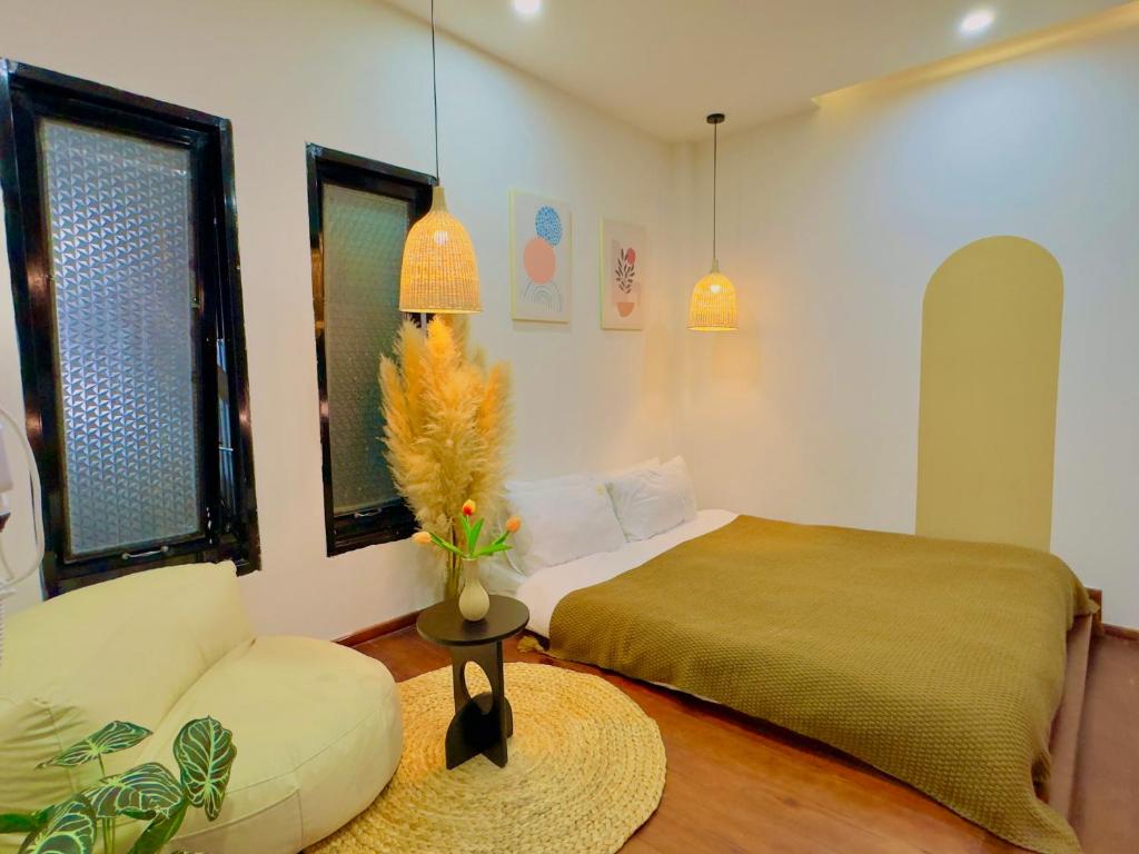 a bedroom with a bed and a couch and windows at Beyoung Hotel Dalat in Da Thanh
