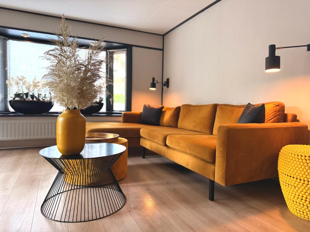 a living room with a couch and a table at Gezellig chalet met 2 slaapkamers aan bosrand in Erm