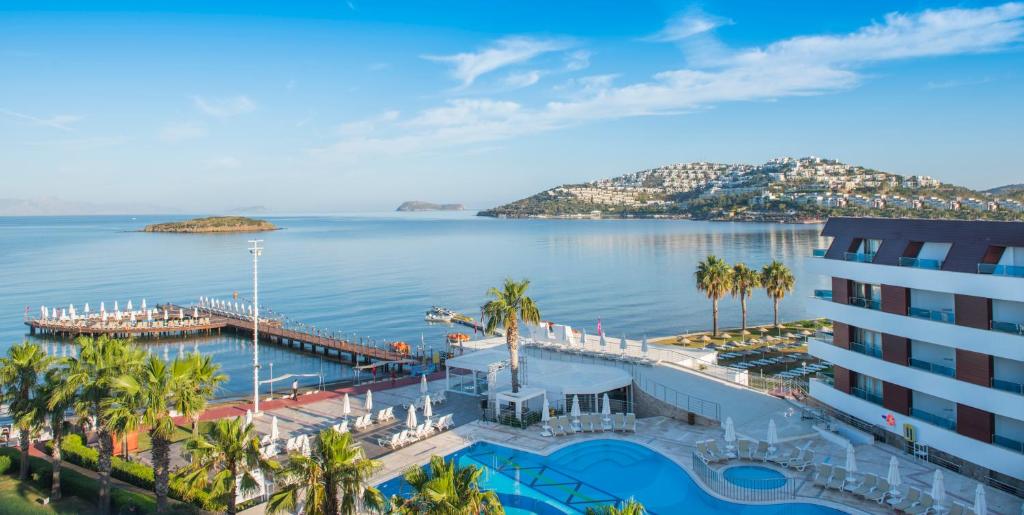 a view of a hotel and the water with palm trees at Azure By Yelken Hotel in Turgutreis