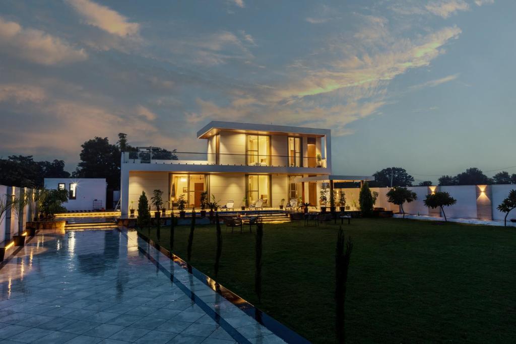 a large house with a pool in front of it at SaffronStays Raaga - luxury 4BR villa with private pool, lawns, gazebos & sweeping Aravalli hill views in Udaipur