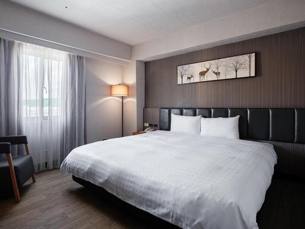 a hotel room with a large bed with white sheets at GUIDE HOTEL Kenting Resort in Hengchun South Gate