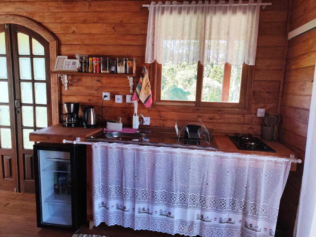 a kitchen with a counter and a sink in a cabin at Eco Chalé Urupema in Urupema