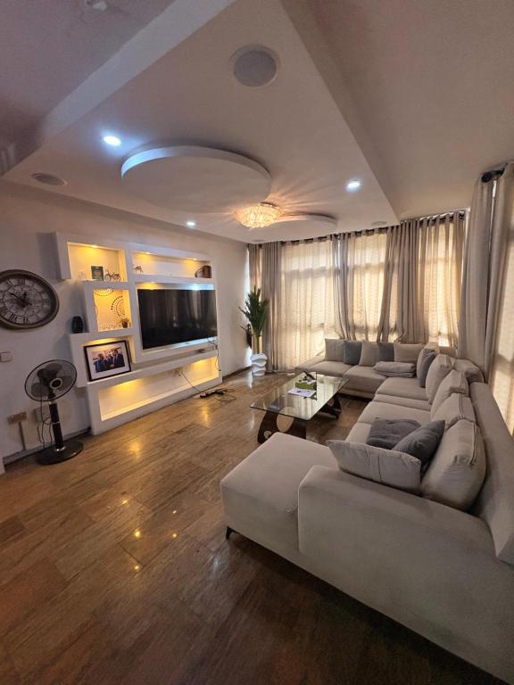 a large living room with a couch and a tv at IBIZA LAGoS in Lagos