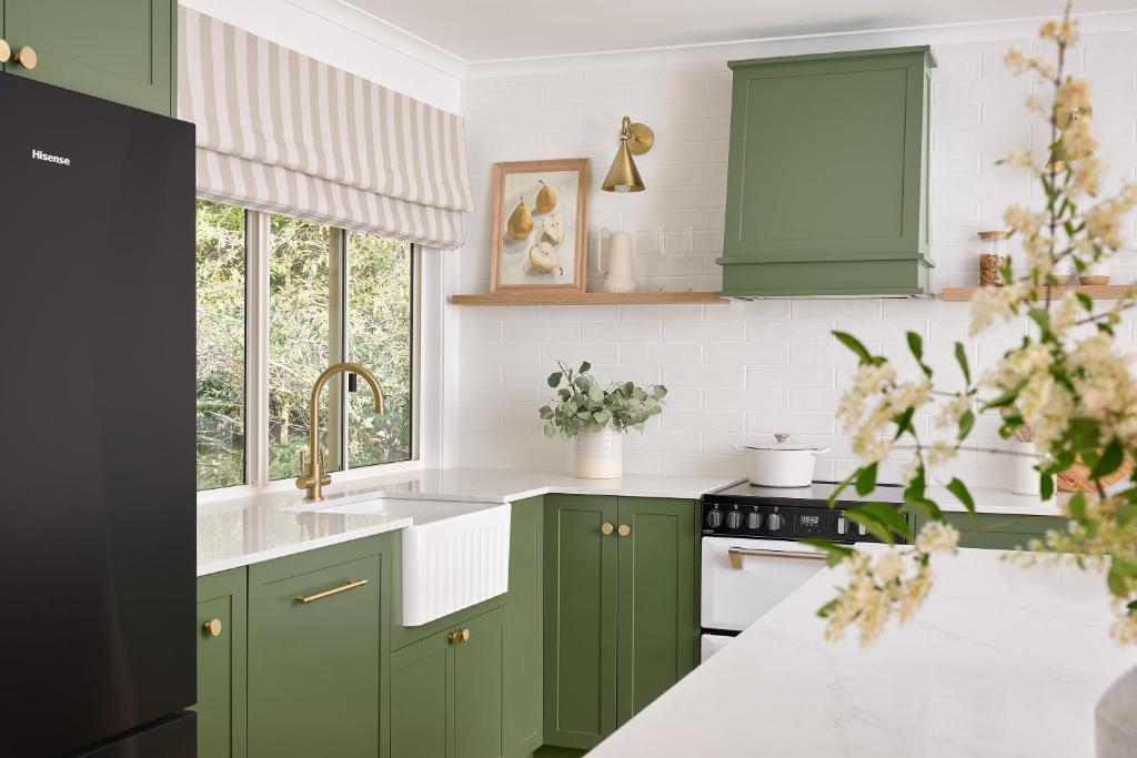 a kitchen with green cabinets and a sink at Oak Ridge Cottage in Maleny