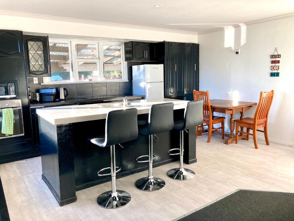 a kitchen with black cabinets and a table and chairs at Oceans Edge Three-bed rooms spacious house in Bluff in Bluff
