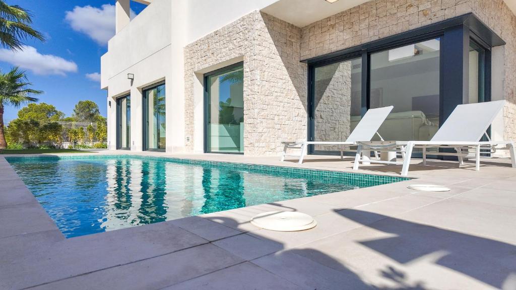 a villa with a swimming pool and two lounge chairs at Family Villa Horizonte in Cala de Finestrat