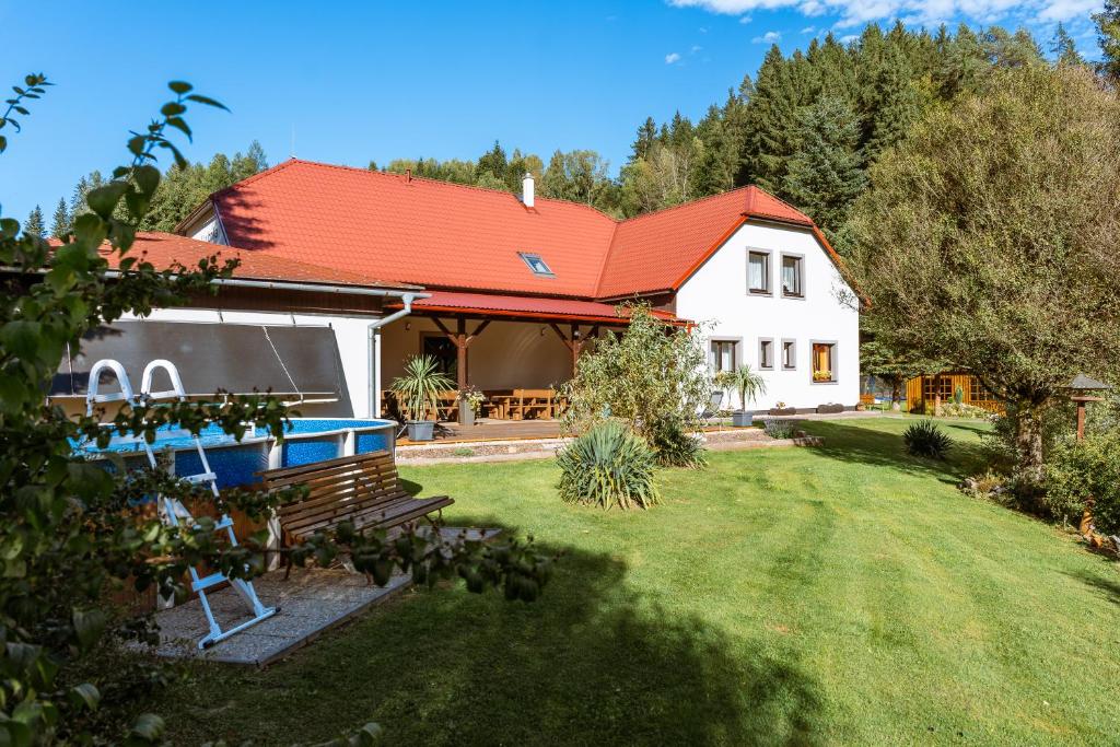 a house with a red roof and a yard at Penzion U rybníka in Šumperk