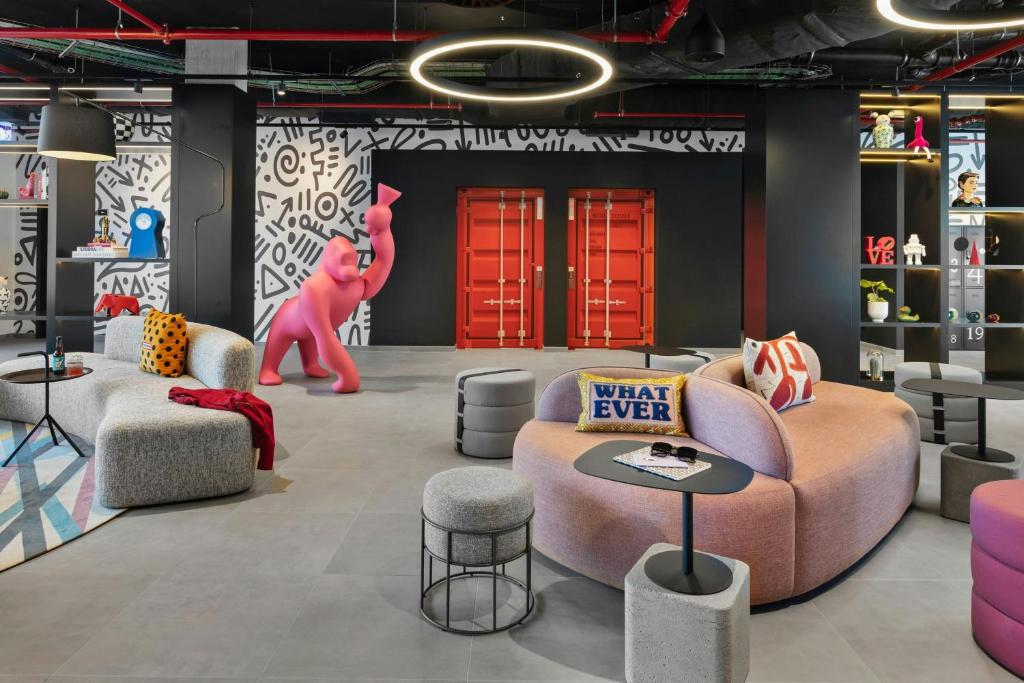 A colorful lobby lounge with curved seating, patterned walls and a pink bear sculpture.