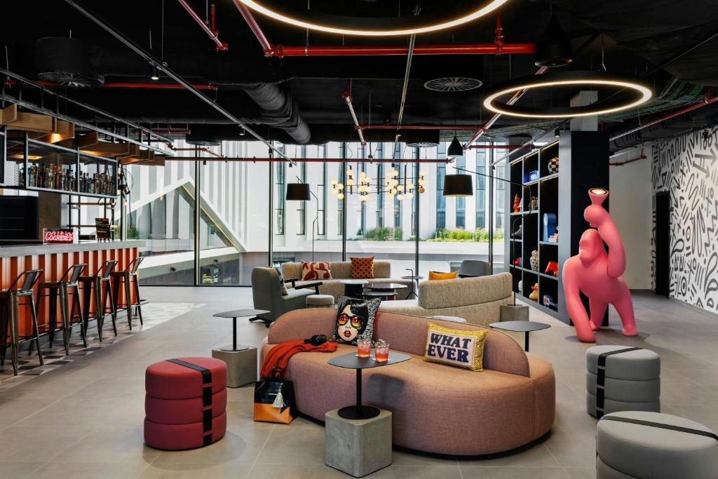 Un vestíbulo con sofás y una estatua de oso rosa. en Moxy Alfragide Lisboa, en Alfragide
