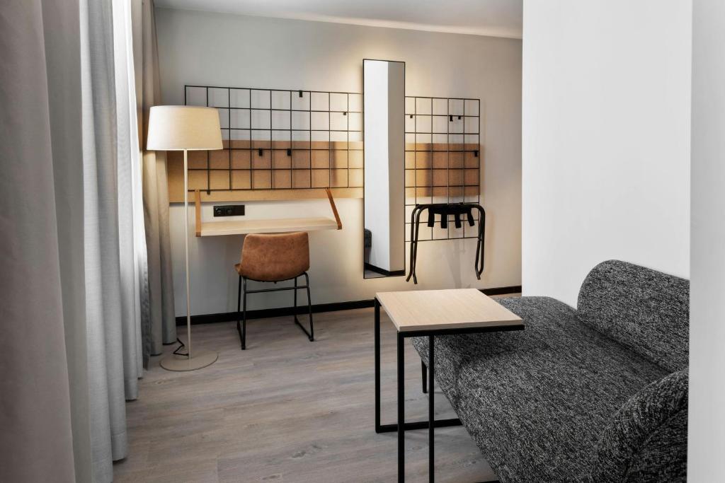 A compact sitting area with a sofa, coffee table, desk, and full-length mirror.