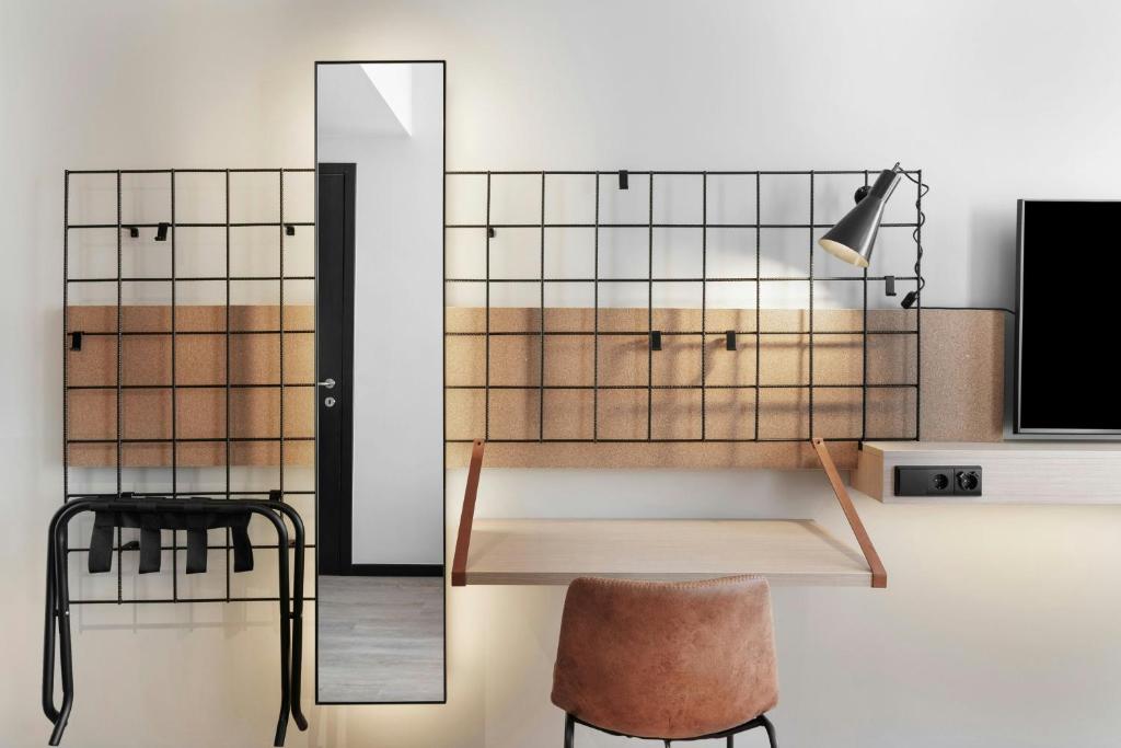 A wall-mounted desk and chair sit beneath a storage grid opposite a full-length mirror.
