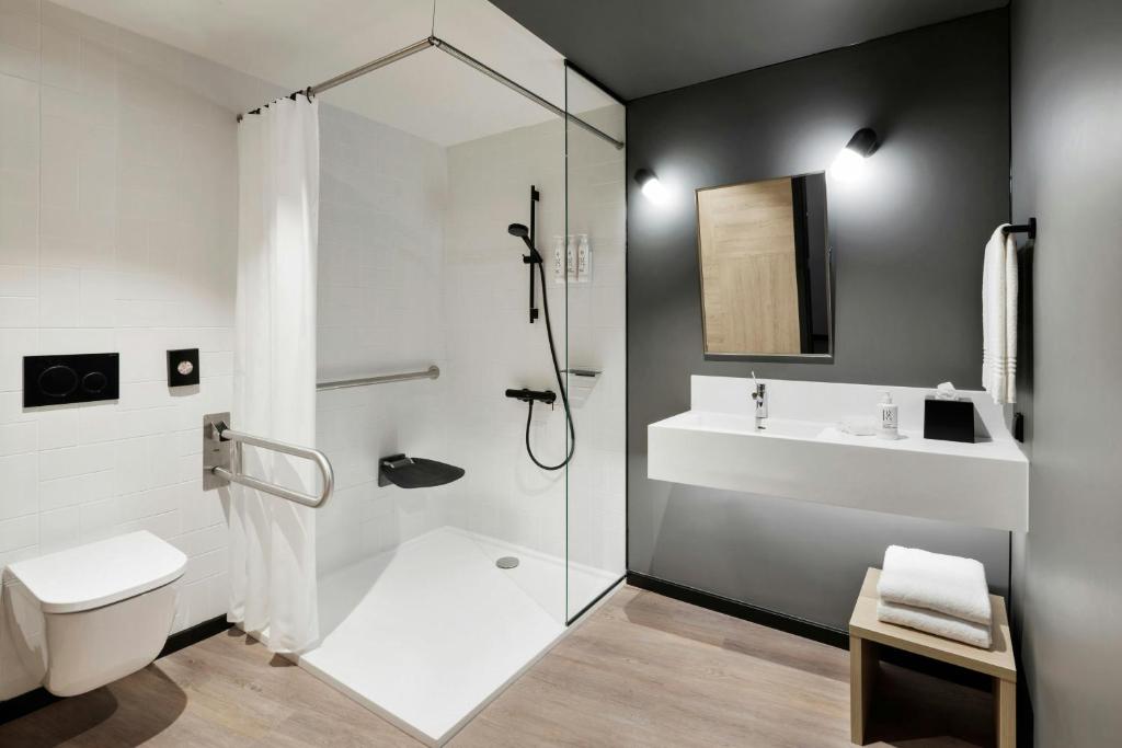 A contemporary accessible bathroom with a walk-in shower, toilet and wide vanity.