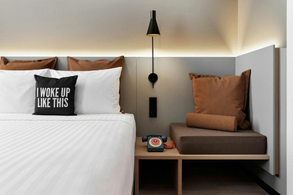 The bedside area combines a made bed, wall light, telephone, and a built-in upholstered seat.