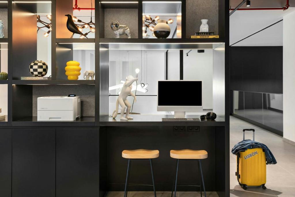 A built-in work counter with two stools, a monitor, printer and display shelving.