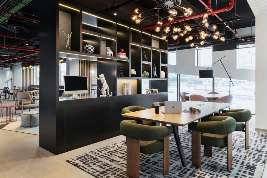 A stylish shared workspace with a communal table, laptop seating and large windows.