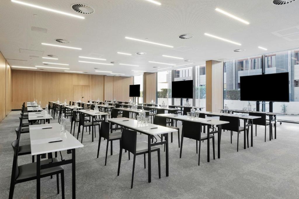 A large dining room set with rows of tables, chairs and wall-mounted screens.