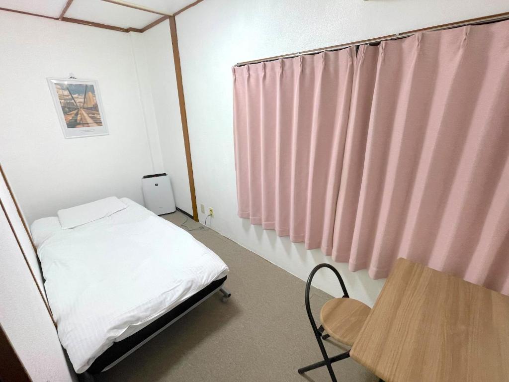 ein Krankenhauszimmer mit einem Bett und einem Tisch in der Unterkunft ゲストハウスひわまり セルフチェックイン 瓦町すぐ in Takamatsu