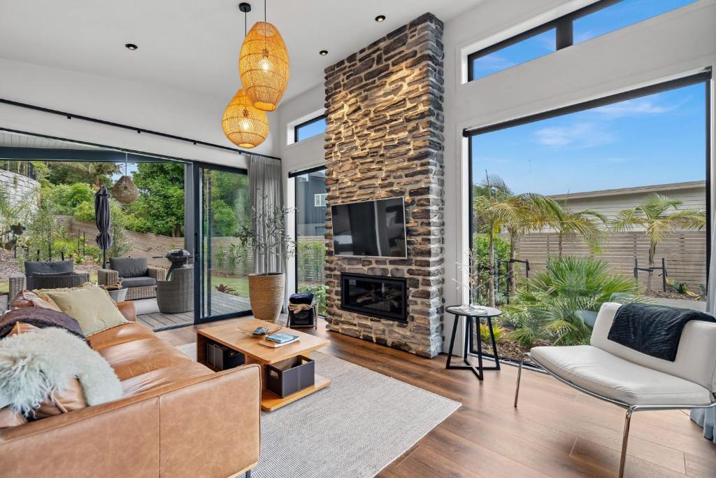 a living room with a couch and a fireplace at Boutique Coastal Retreat with Bath Walk to Beach in Mangawhai