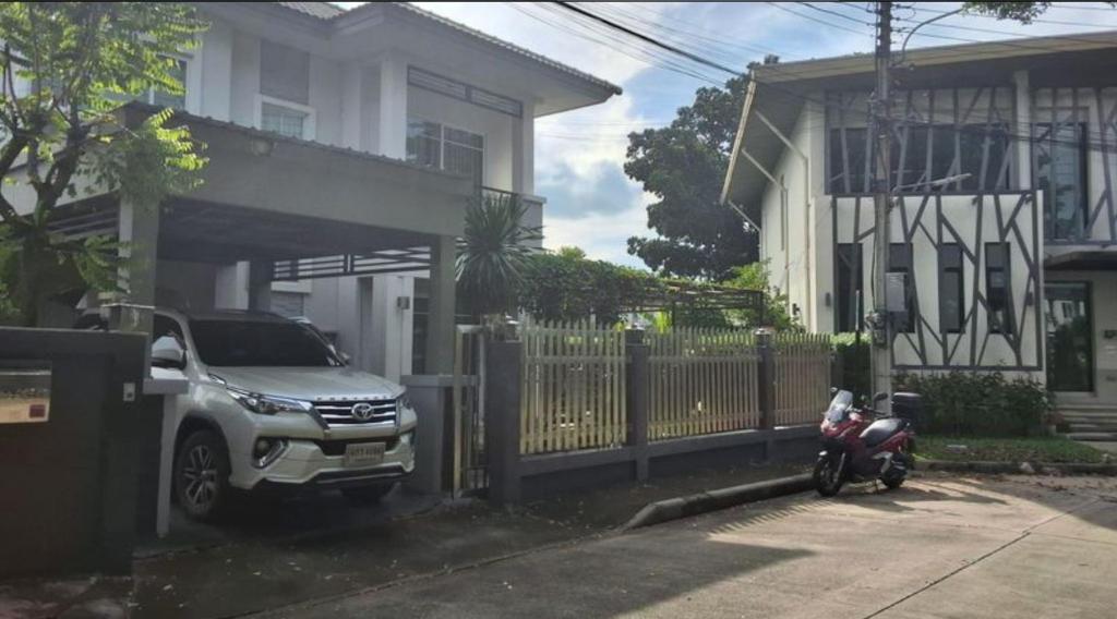 a car parked in front of a house with a motorcycle at Spacious Entire House with shared Fitness Room and Shared Indoor Pool in club in Pathum Thani