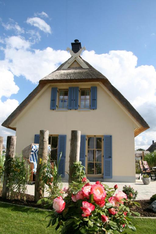a small white house with blue windows and roses at FeHa Ankerplatz mit Sauna und sonniger Terrasse in Parow