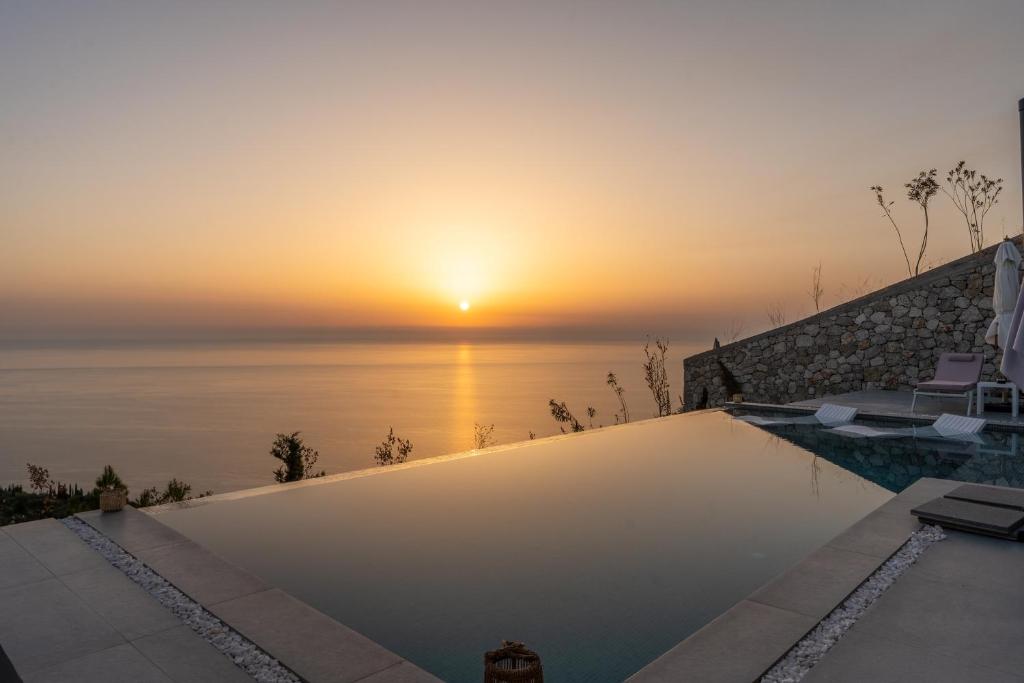 a swimming pool with a sunset in the background at Villa Lulu Lefkada in Kalamitsi