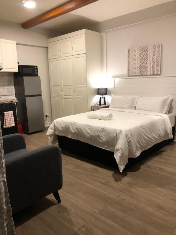 a bedroom with a large white bed and a chair at Easy Escape Studio in Lusaka