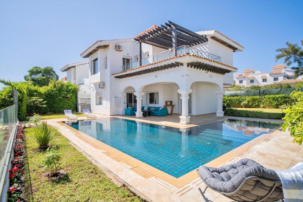 a villa with a swimming pool in front of a house at Villa Aurea Pool, Panoramic Views in Tangier