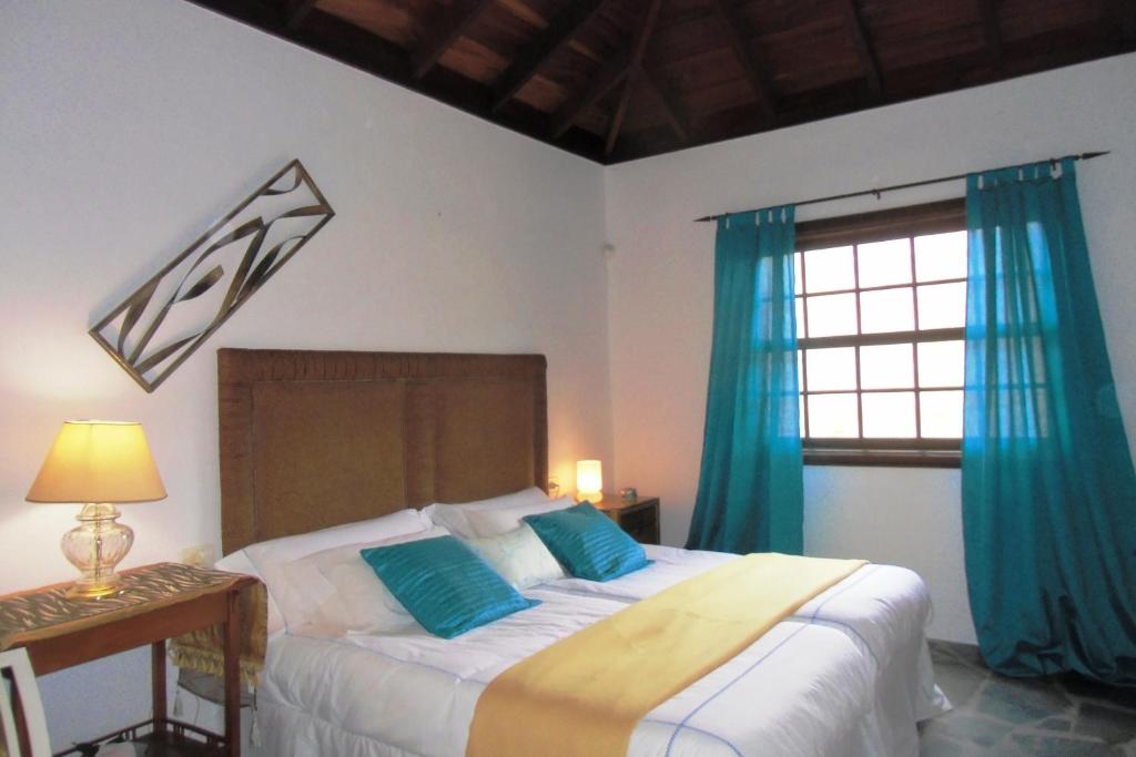 a bedroom with a bed with blue curtains and a window at Finca Chimaca in Arona