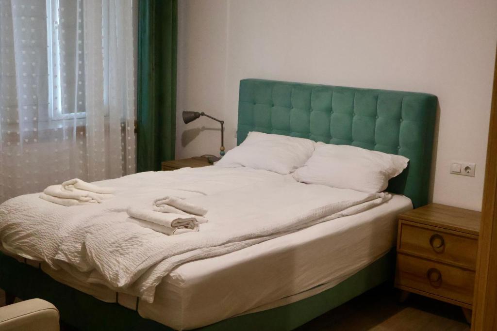 a bed with a green headboard and towels on it at Casa Centrale with Free Parking in Plovdiv