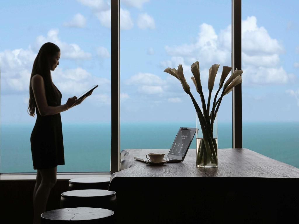 a woman standing in front of a window reading a book at Pullman Vung Tau in Vung Tau