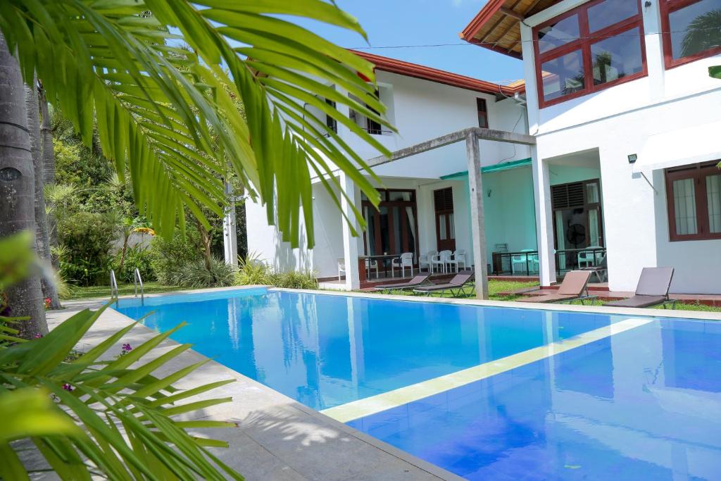 une piscine devant une maison dans l'établissement Harris Villa, à Hikkaduwa