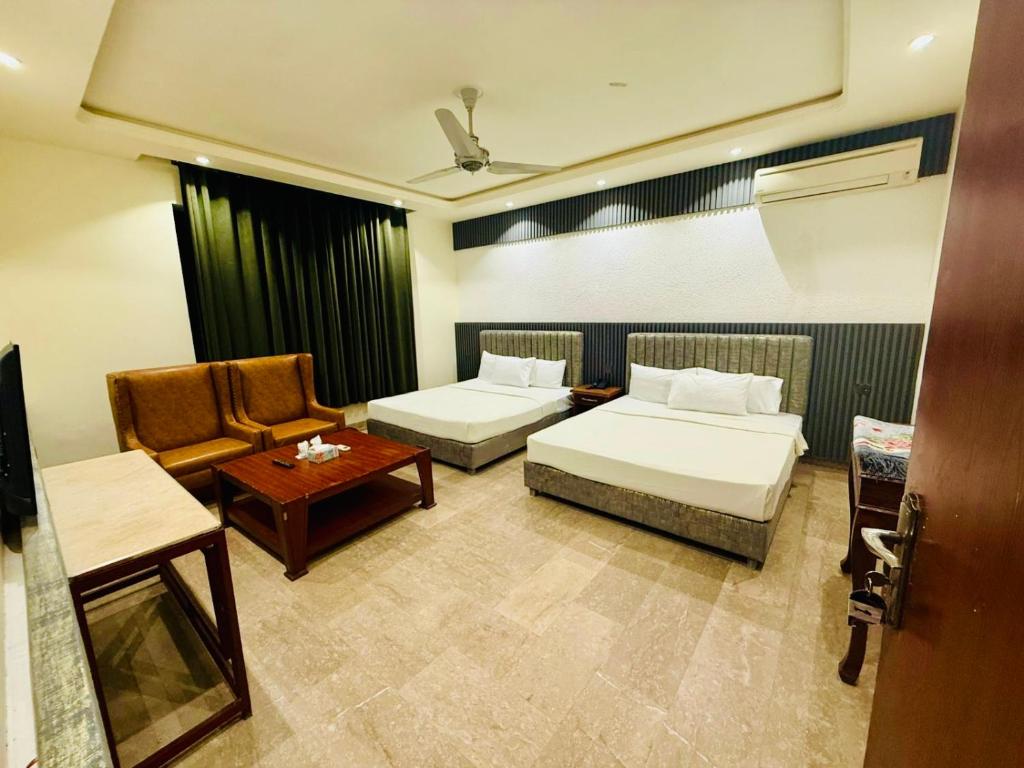 a hotel room with two beds and a chair at Blue Moon Residency Jinnah Super in Islamabad