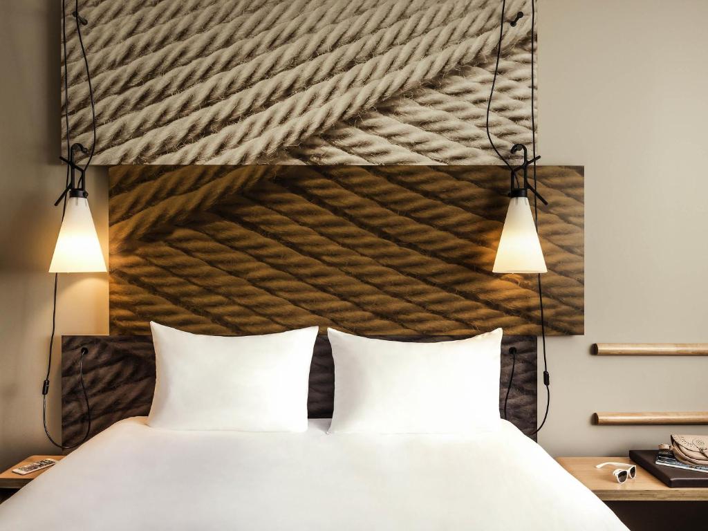 a bed with two white pillows and two lights at ibis Saint Quentin en Yvelines - Vélodrome in Montigny-le-Bretonneux