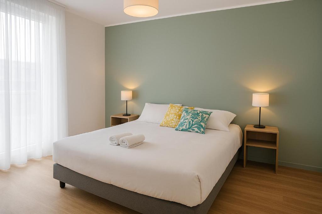 una camera da letto con un grande letto bianco con due lampade di Zenao Appart'hôtels Le Raincy Thiers a Le Raincy