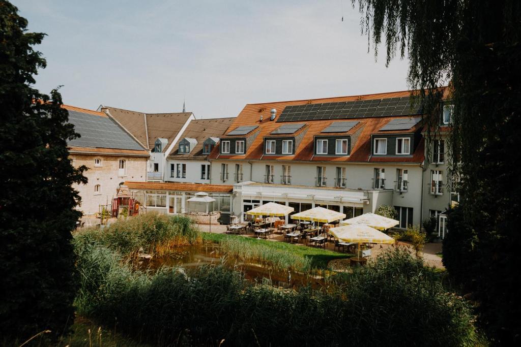 a large building with tables and umbrellas in front of it at Hotel am Schloß Apolda in Apolda