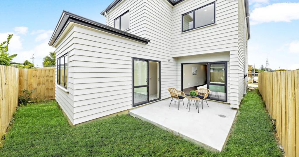 a white house with two chairs and a table at Modern Family Retreat Near Auckland City & Airport in Auckland