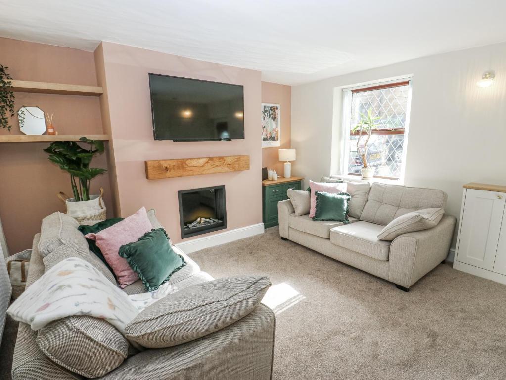 a living room with two couches and a tv at Court Street Cottage in Saddleworth