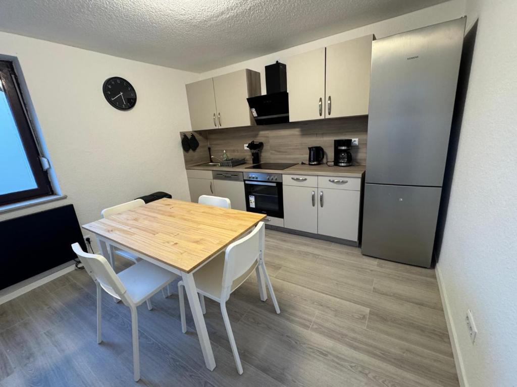 a kitchen with a wooden table and white chairs at bookandstay24 Reinheim-Spachbrücken bei Darmstadt, Frankfurt, Rhein-Main-Gebiet in Reinheim