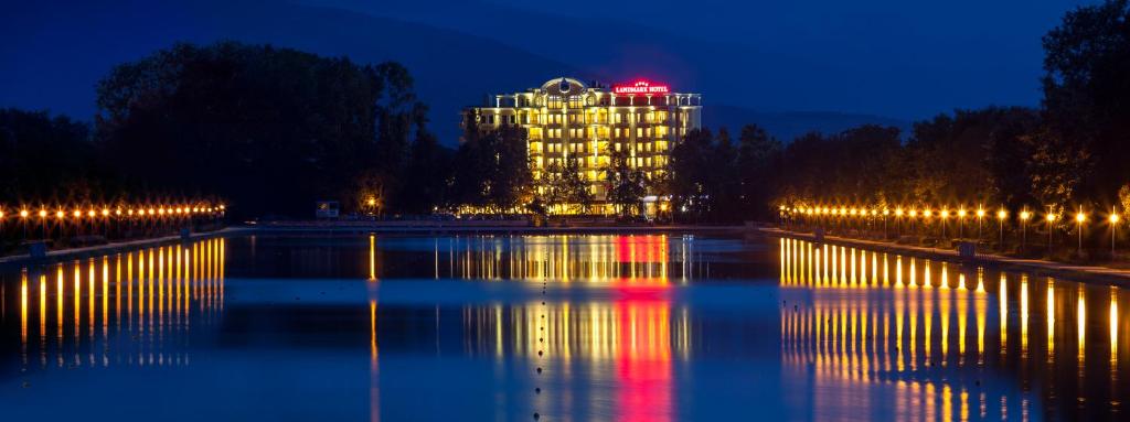 a large building with lights in the water at night at Landmark Creek Hotel & Wellness in Plovdiv