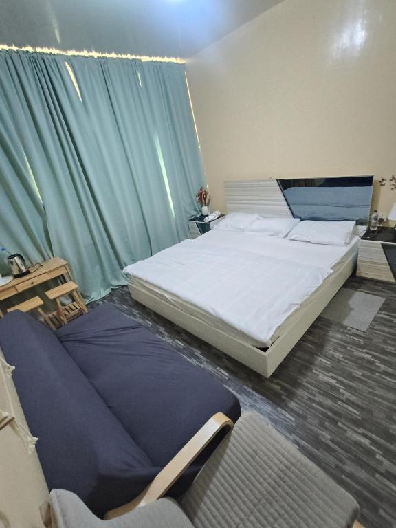 a bedroom with a large bed and a green curtain at Summer home stay 04 in Abu Dhabi
