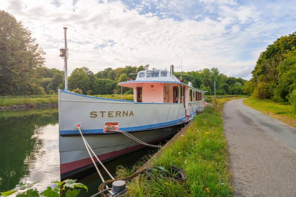 a boat parked on the side of a canal at Sterna boat & suites in Mechelen