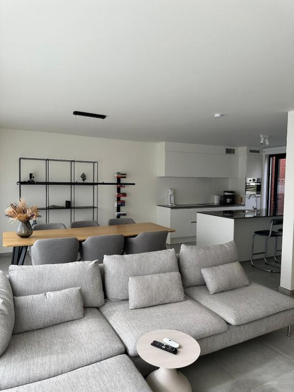 Una sala de estar con un sofá y una cocina. en Beaulivia Maaseik, en Maaseik