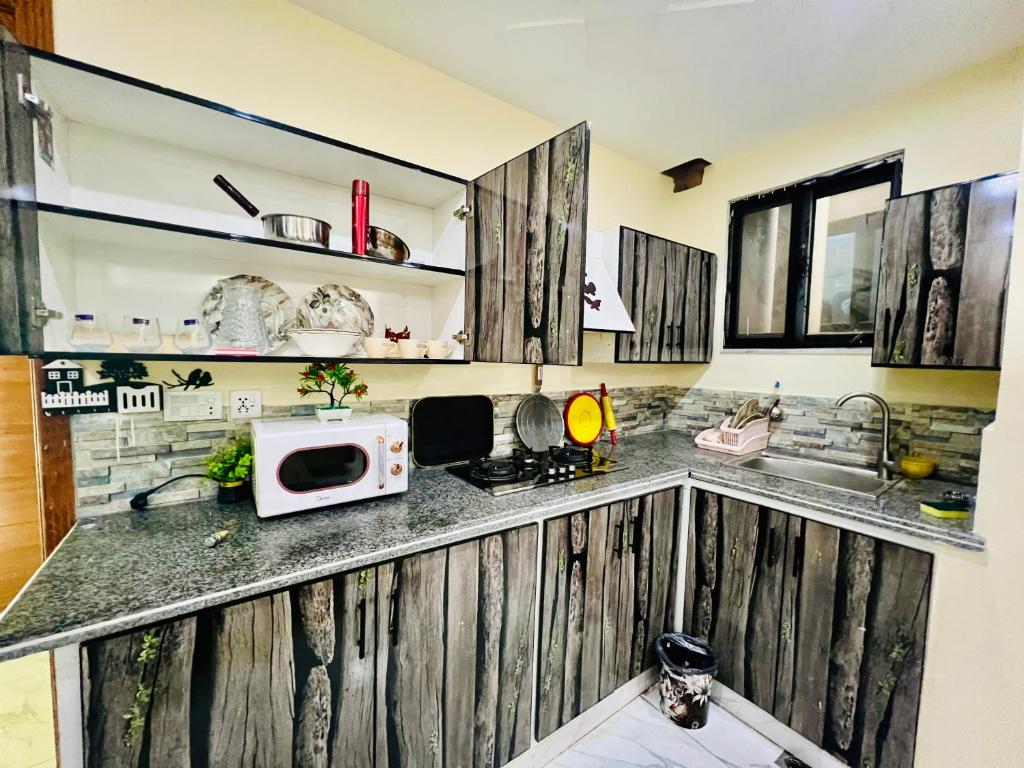a kitchen with wooden cabinets and a microwave on a counter at 1 one bed flat furnished Bahria Town Rawalpindi Islamabad in Rawalpindi