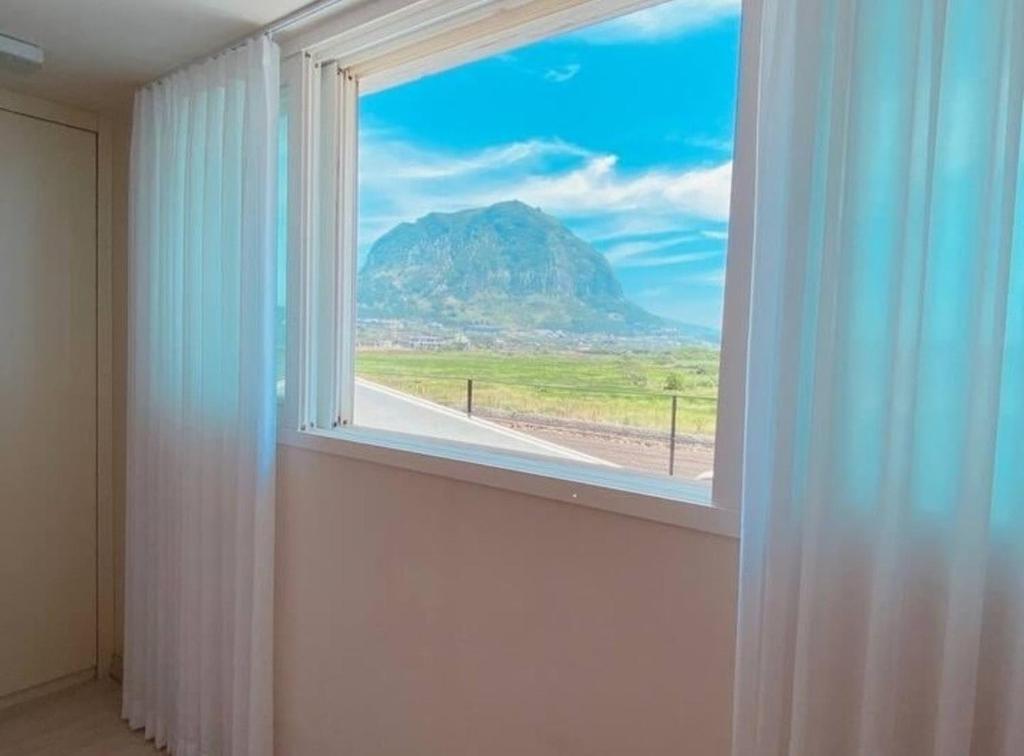 d'une fenêtre avec vue sur la montagne. dans l'établissement 제주 웅장한 산방산뷰 사계2248 해무리동 감성숙소, à Sagye-ri