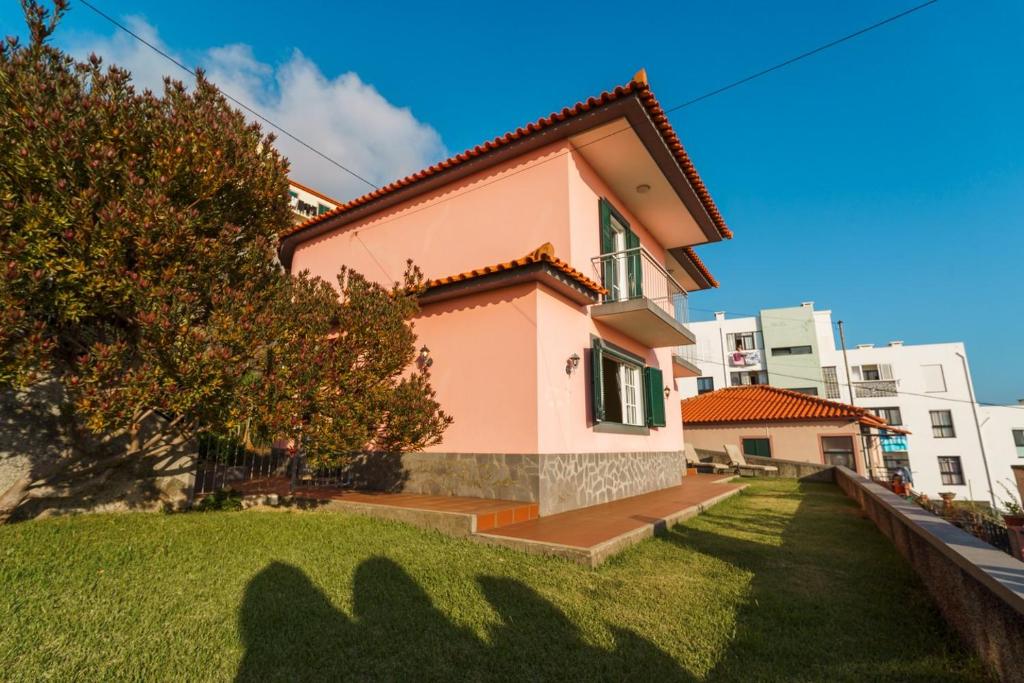 a small pink house with a green yard at GuestReady - Sea-View Retreat in Madeira in Santo António