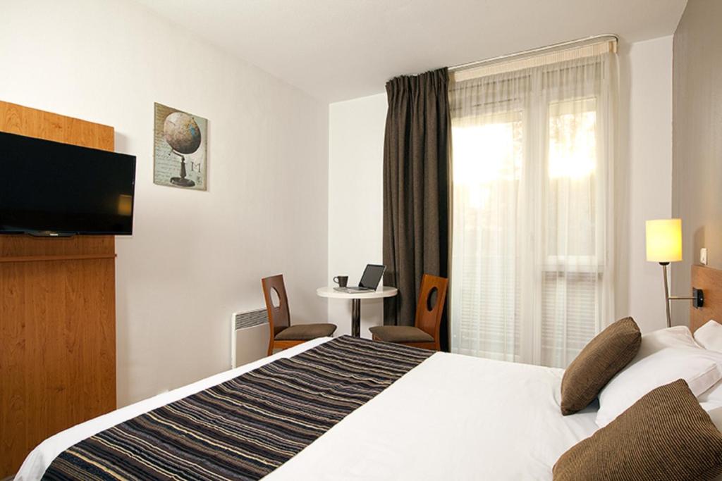 a hotel room with a large bed and a window at Séjours &amp; Affaires Paris Ivry in Ivry-sur-Seine