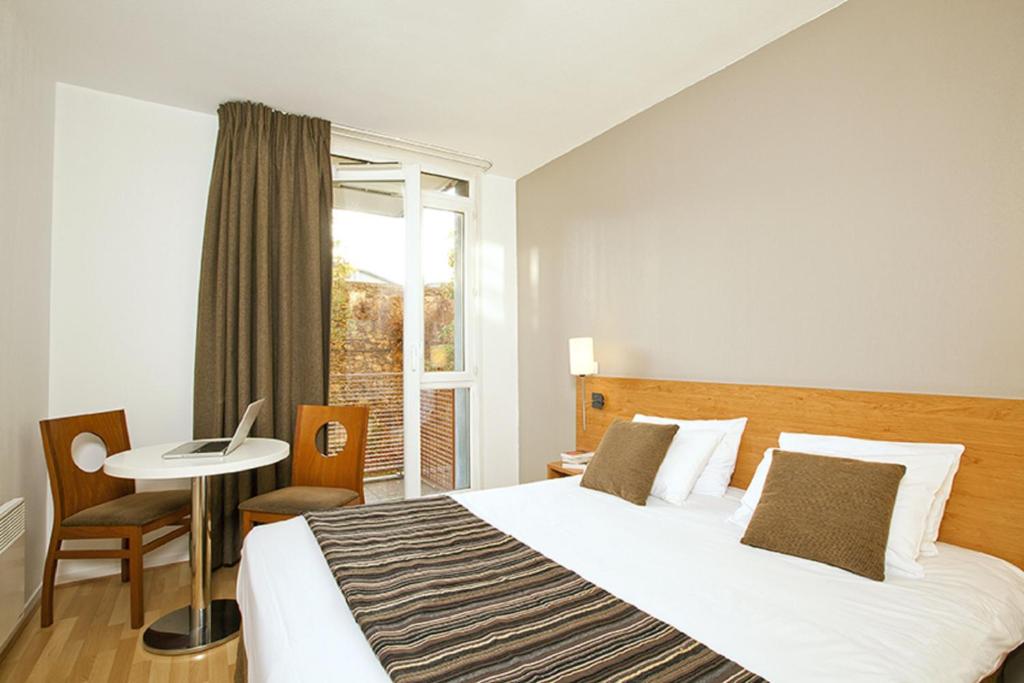 um quarto com uma cama, uma mesa e uma janela em Séjours & Affaires Paris Ivry em Ivry-sur-Seine
