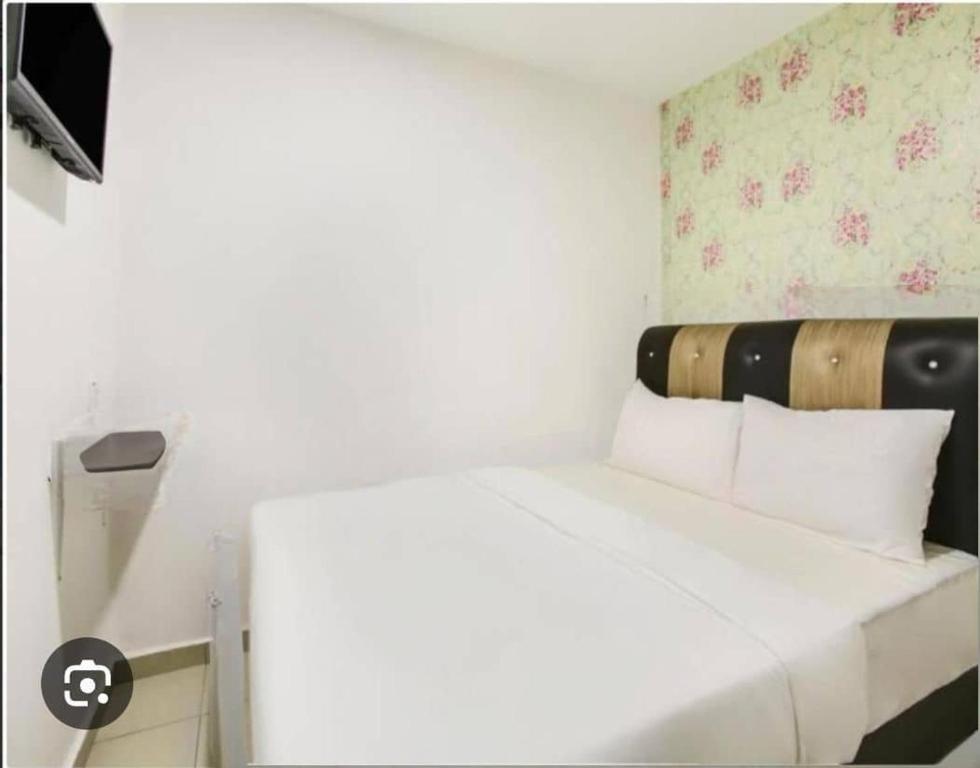 a bedroom with a white bed with a wooden headboard at Hotel Melaka INN in Melaka